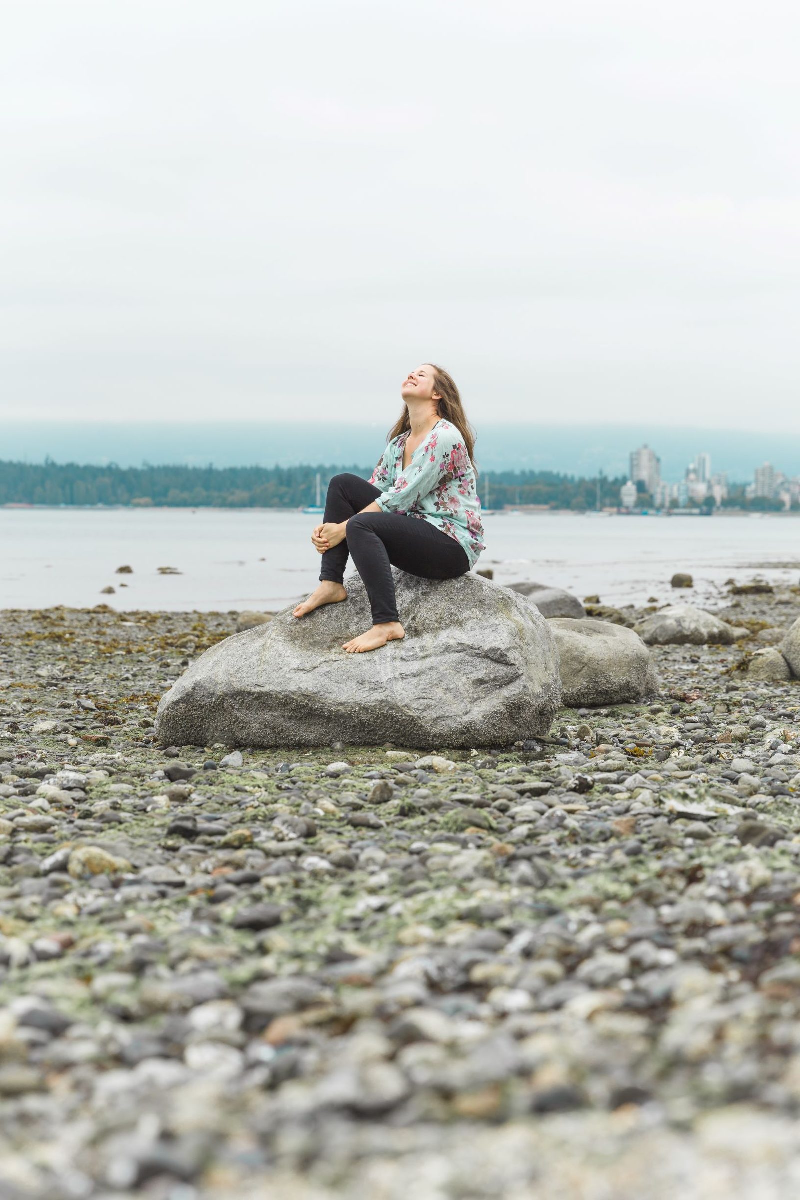 Danielle sitting quietly on a rock by the shore