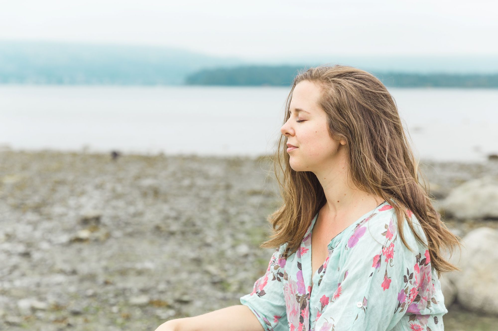 Danielle Leclair by the water, eyes closed in a calm moment